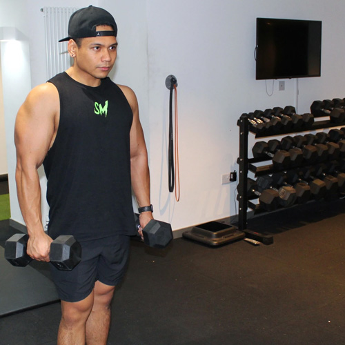 An image of Thom lifting dumbells on both hands while looking serious